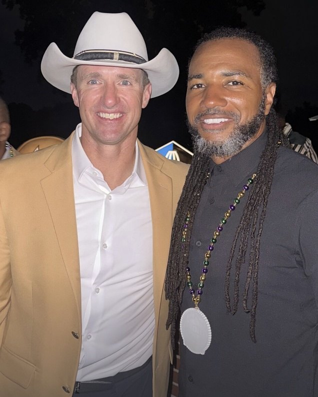 Usama Young smiling at an evening event, wearing beads and a medallion